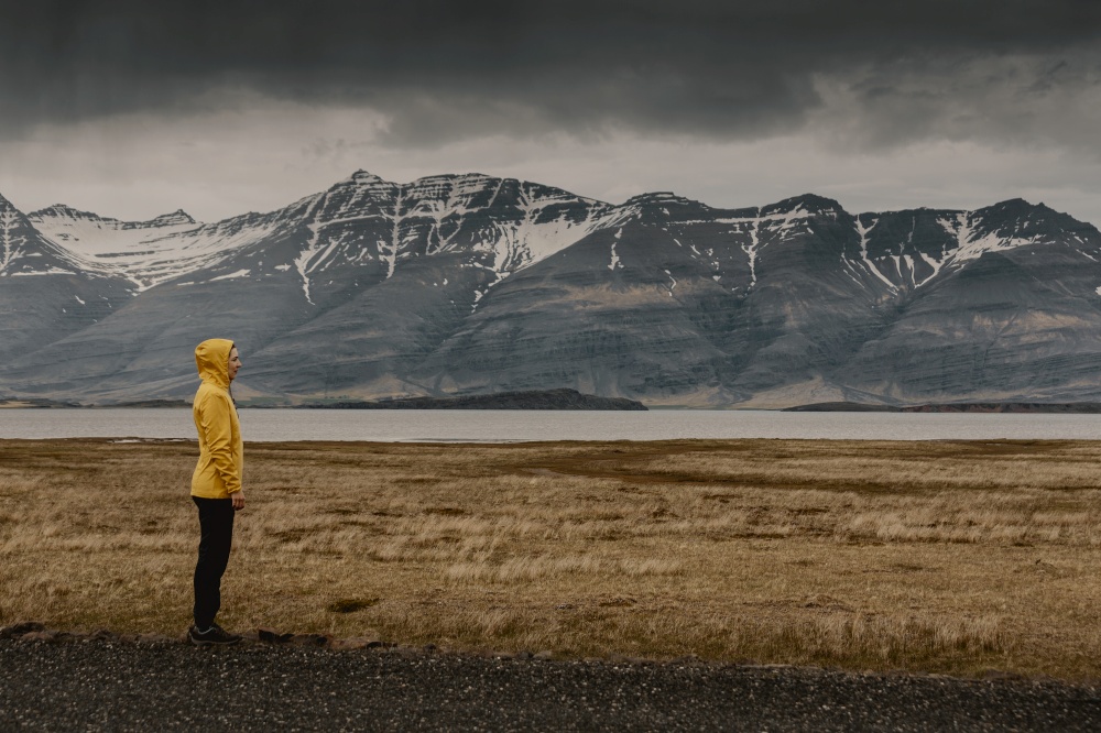 Woman in yellow contemplating the landscape; Iceland