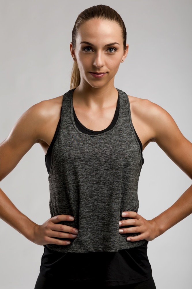 Young fitness woman against a gray background