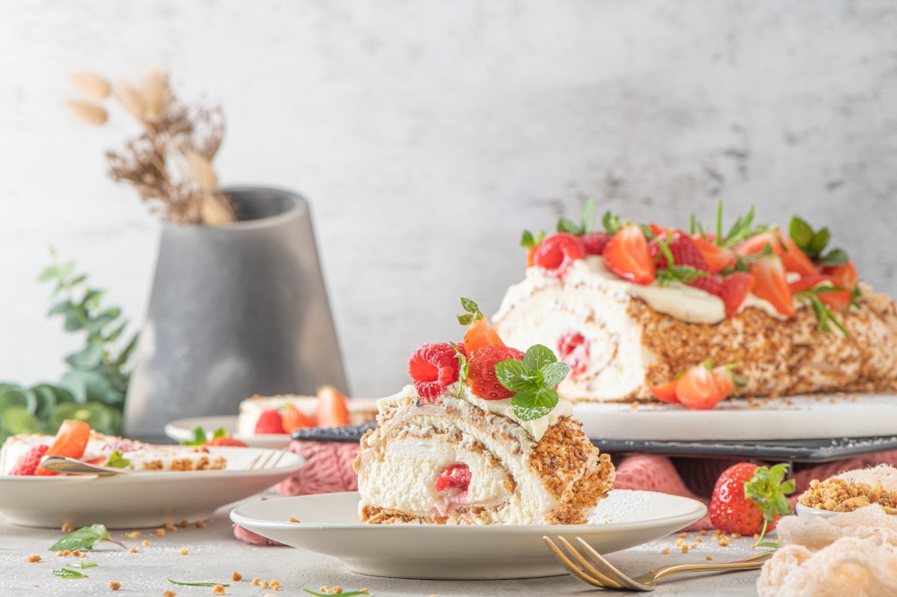 Meringue roll with a gentle airy cream, crunchy peanut, mint, rosemary and filling with raspberries and strawberries. Pavlova summer sweet dessert.