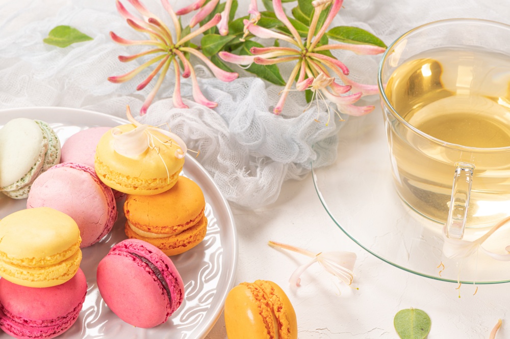 Colorful french macaroon cakes. Macaroons with jasmine flowers and tea on white table background. Selective focus