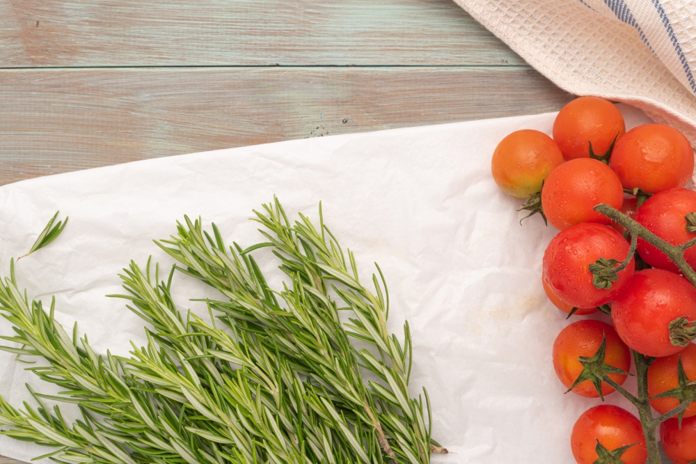 The branch of tomatoes and rosemary are on the wrinkled paper. Italian cuisine