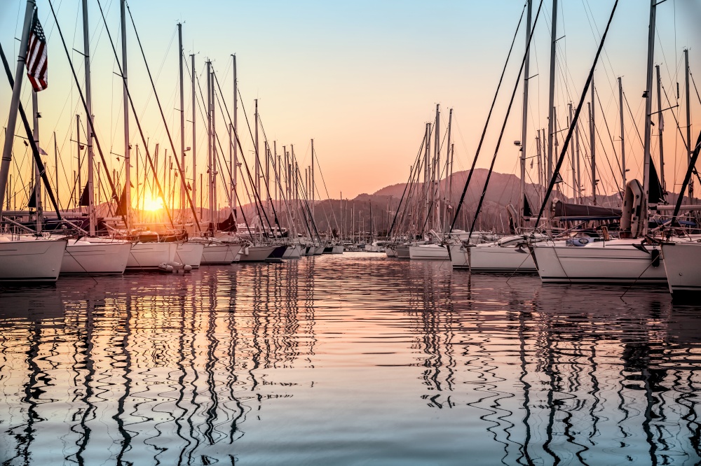 Beautiful sailboats moored in the dock, amazing view of gorgeous white sail boats over mountains background in mild sunset light, luxury summer vacation in Marmaris, Turkey