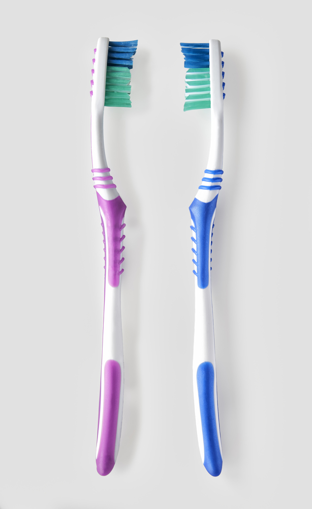 Overhead view of his and hers toothbrush on white bacground