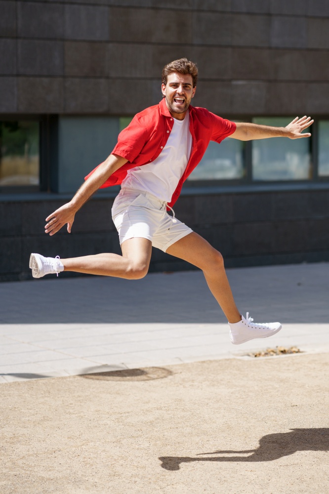 Young man wearing casual clothes jumping in urban background.. Man wearing casual clothes jumping in urban background.