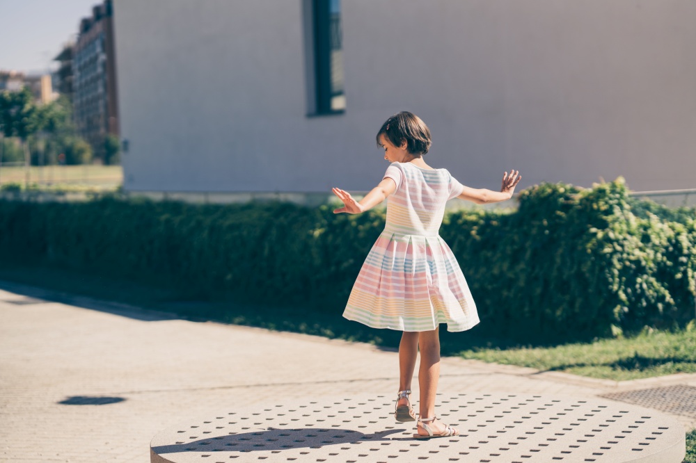 Happy 9-year-old girl in a pretty dress playing in the street. Happy 9-year-old girl in a pretty dress playing