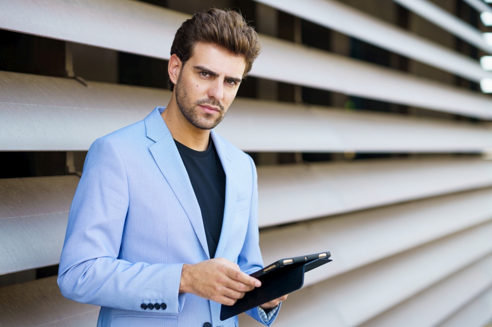 Man in a suit using a digital tablet outdoors. Businessman using a digital tablet near an office building