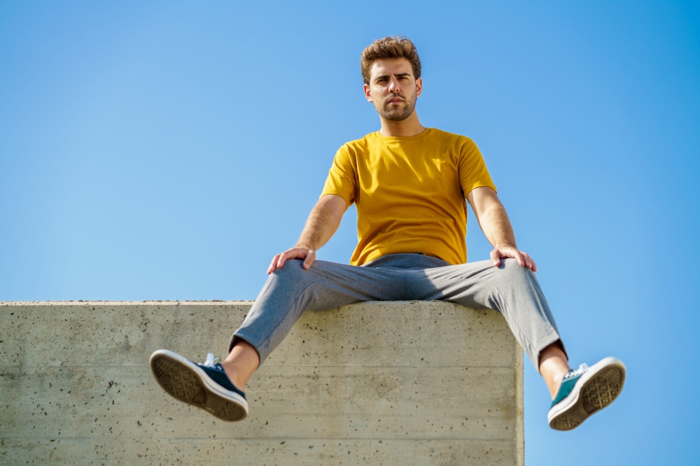 Young man sitting on a ledge looking around. Man sitting on a ledge looking around