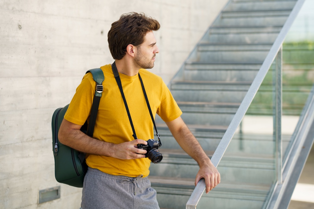 Millennial man using a SLR camera outdoors. Millennial man taking photographs with a SLR camera