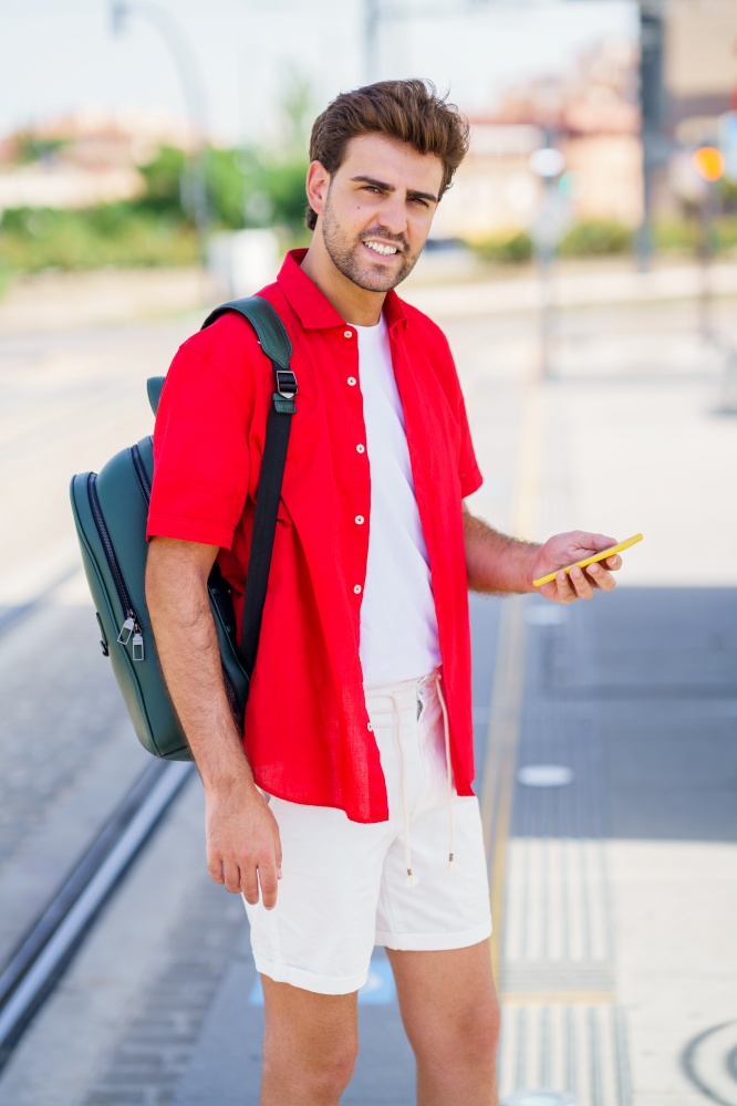 Student male waiting for a train at an outside station. Young man waiting for a train at an outside station