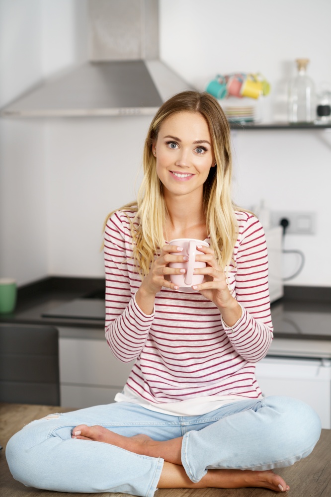 Smiling caucasian woman holding a cup of coffee at home.. Smiling woman holding a cup of coffee at home.