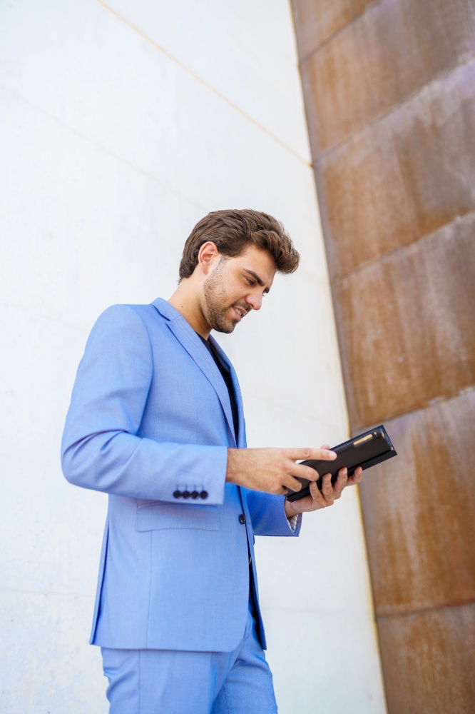 Young businessman using a digital tablet near an office building. Businessman using a digital tablet near an office building