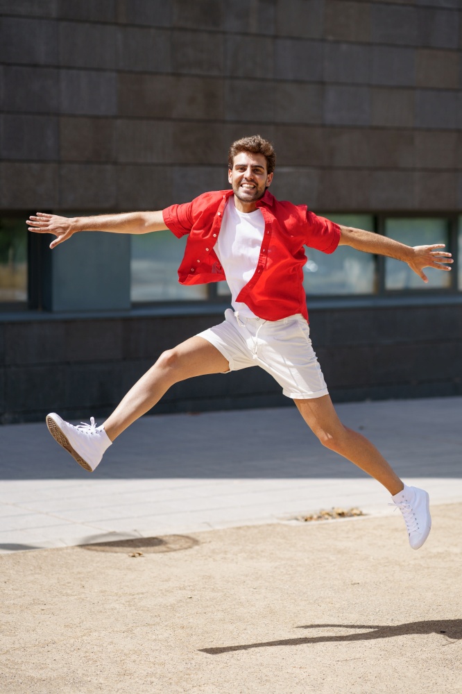 Young man wearing casual clothes jumping in urban background.. Man wearing casual clothes jumping in urban background.