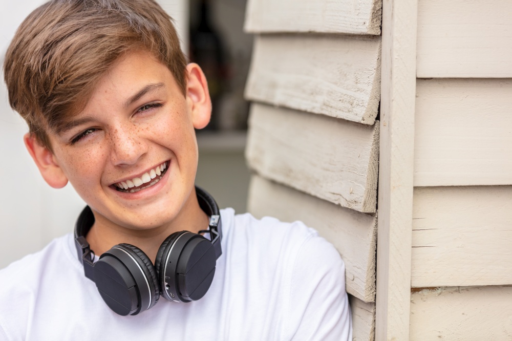 Teenage boy wearing wirless bluetooth headphones and laughing