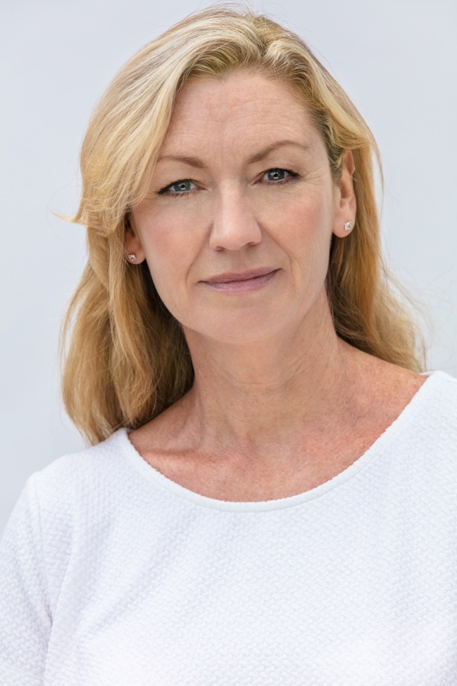 Studio portrait of an attractive middle aged blonde woman smiling on a white background