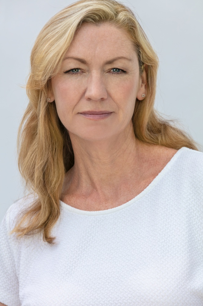 Studio portrait of an attractive middle aged blonde woman smiling on a white background