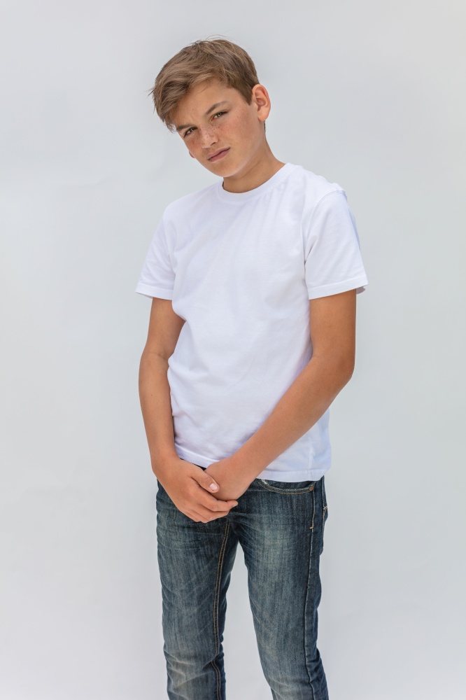 White background studio portrait of a boy teenager teen male child wearing a white t-shirt and blue jeans