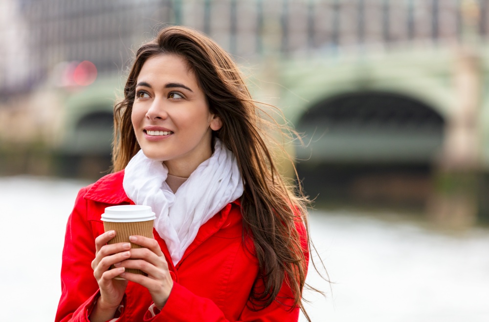 Girl or young woman in a modern city, drinking coffee by Westminster Bridge over the River Thames,  London, England, Great Britain