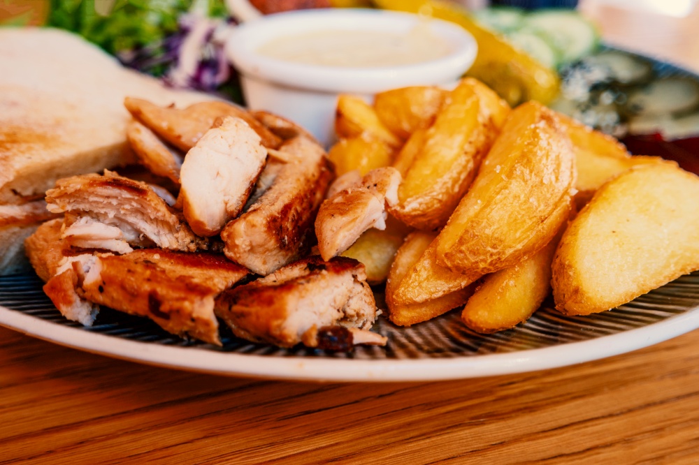 Dish with grilled chicken meat and fryed potato on table in arabian cafe. Dish with grilled chicken meat and fryed potato