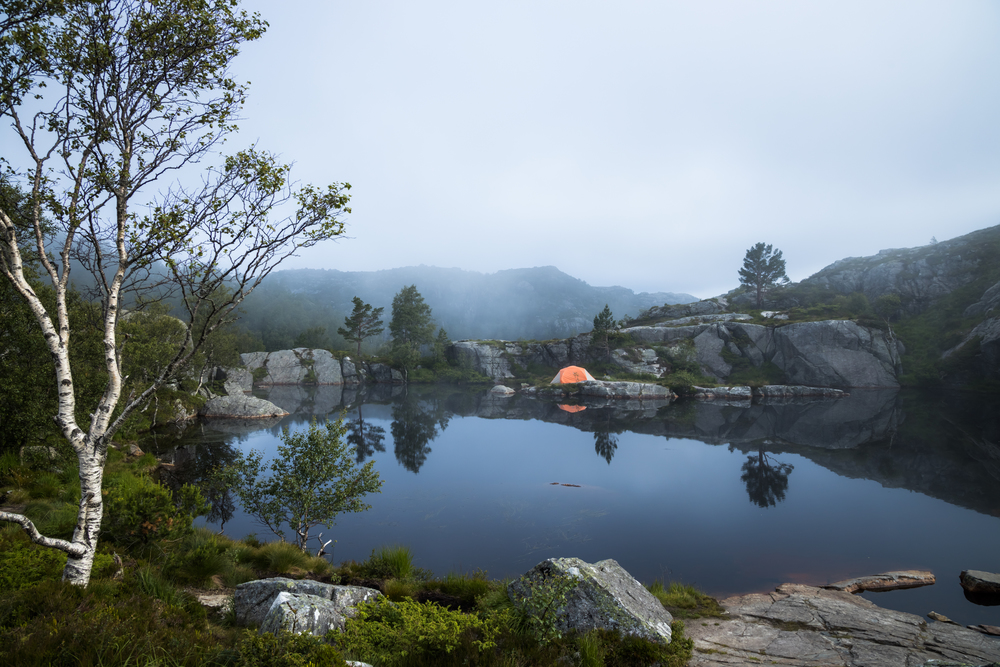 Tourist tent on the shore of a lake in the mountains. Beautiful Nature Norway natural landscape.