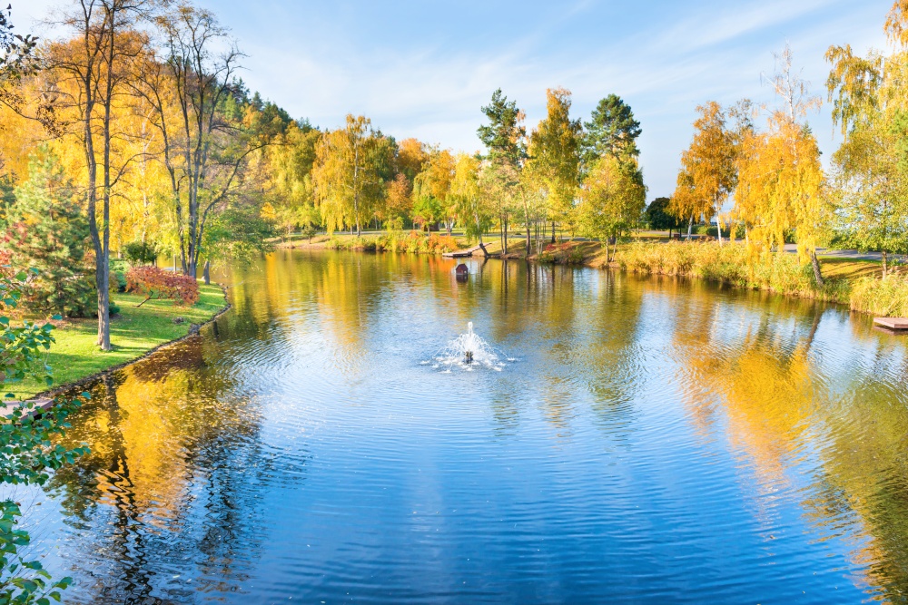 Lake in park with small house and autumn forest and trees