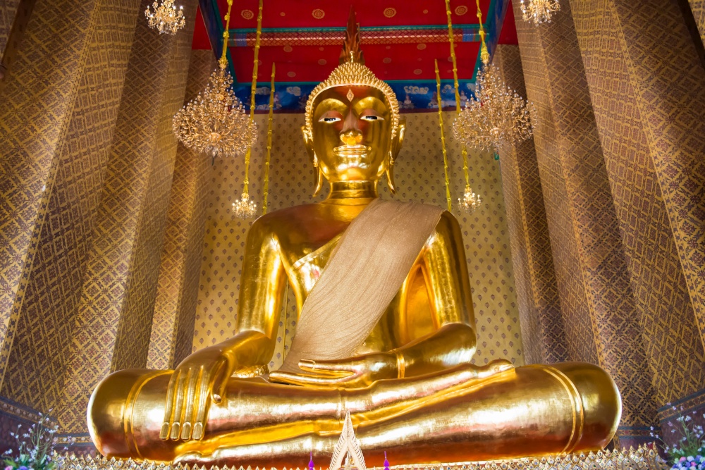 View of big golden statue of sitting Buddha in famous buddhist temple. Wat Kanlayanamit, Bangkok, Thailand