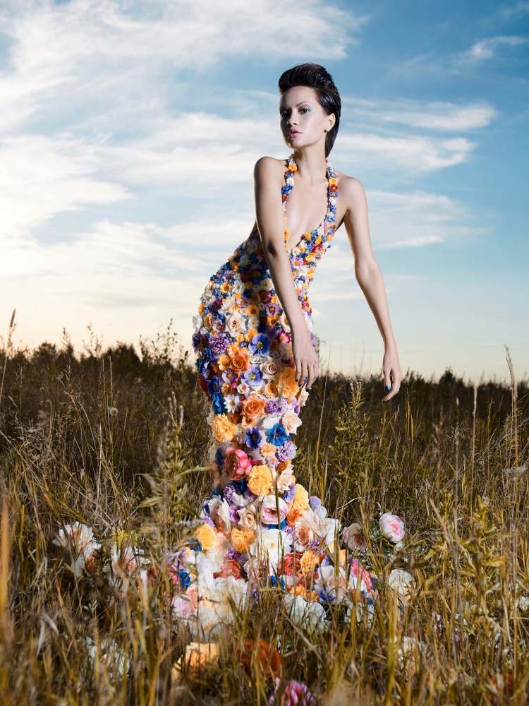 Fashion photo of beautiful lady in dress of flowers. Beautiful woman pose outdors.