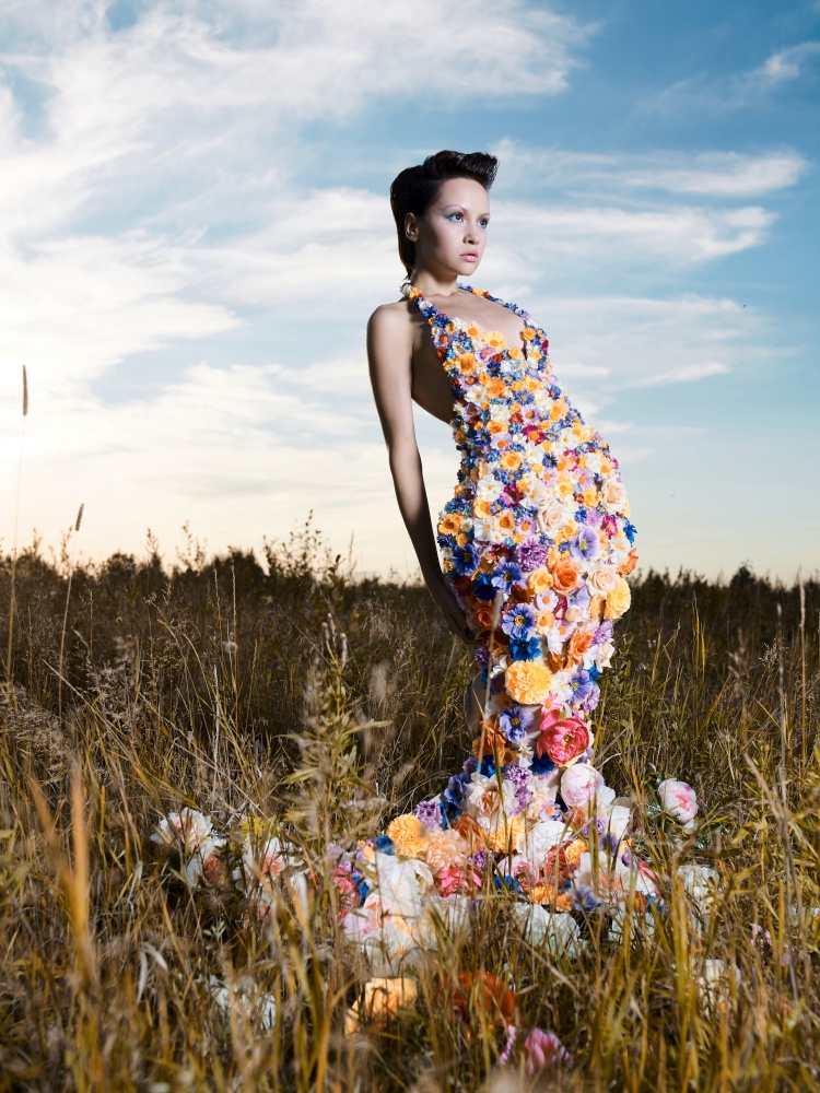 Fashion photo of beautiful lady in dress of flowers. Beautiful woman pose outdors.