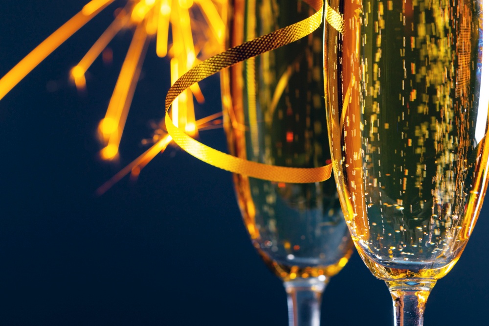 Two glasses of champagne and sparklers lights in the background New Year party celebration concept. Two glasses of champagne