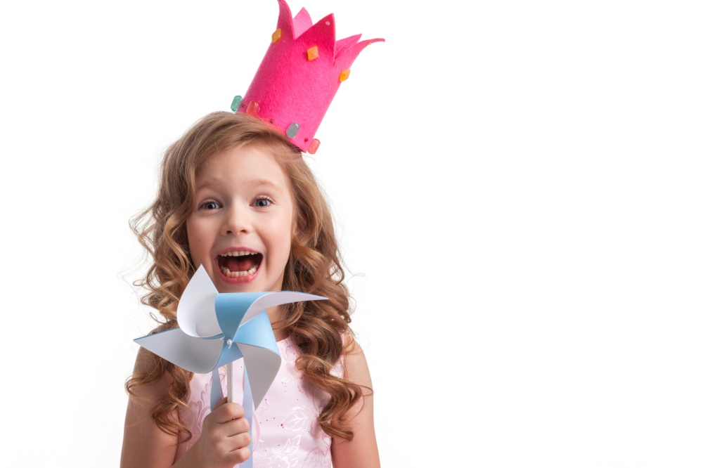 Beautiful little candy princess girl in crown holding pinwheel and smiling. Candy princess girl with pinwheel