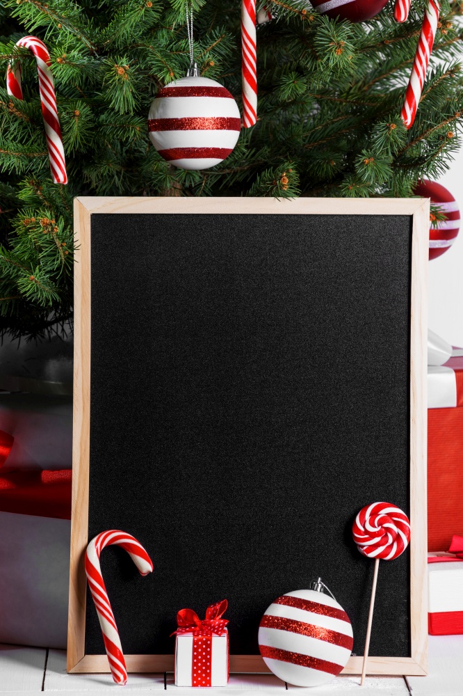 Blank blackboard and Christmas tree branches, red glass ball and candy canes. Blank blackboard and Christmas tree