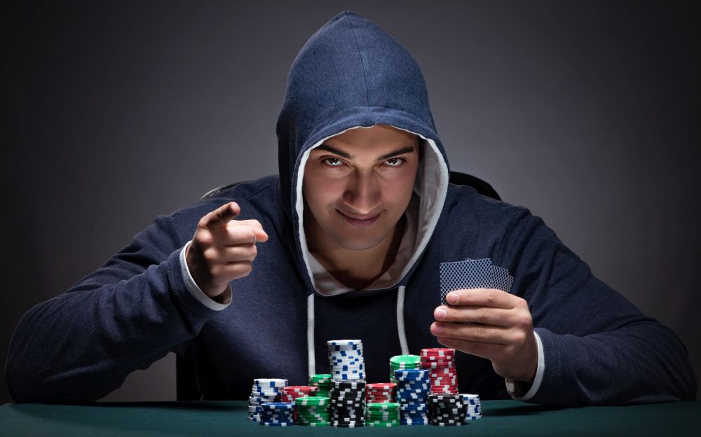 The young man wearing a hoodie with cards and chips gambling. Young man wearing a hoodie with cards and chips gambling