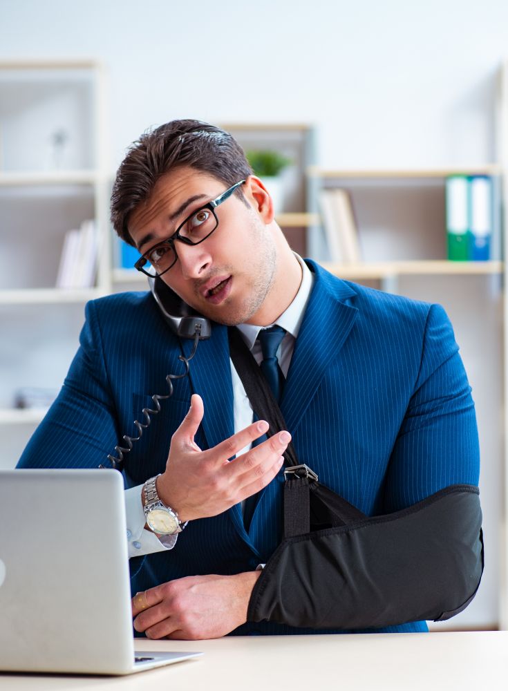 The businessman with broken arm working in office. Businessman with broken arm working in office