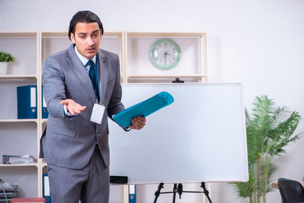 The young businessman standing in front of white board. Young businessman standing in front of white board