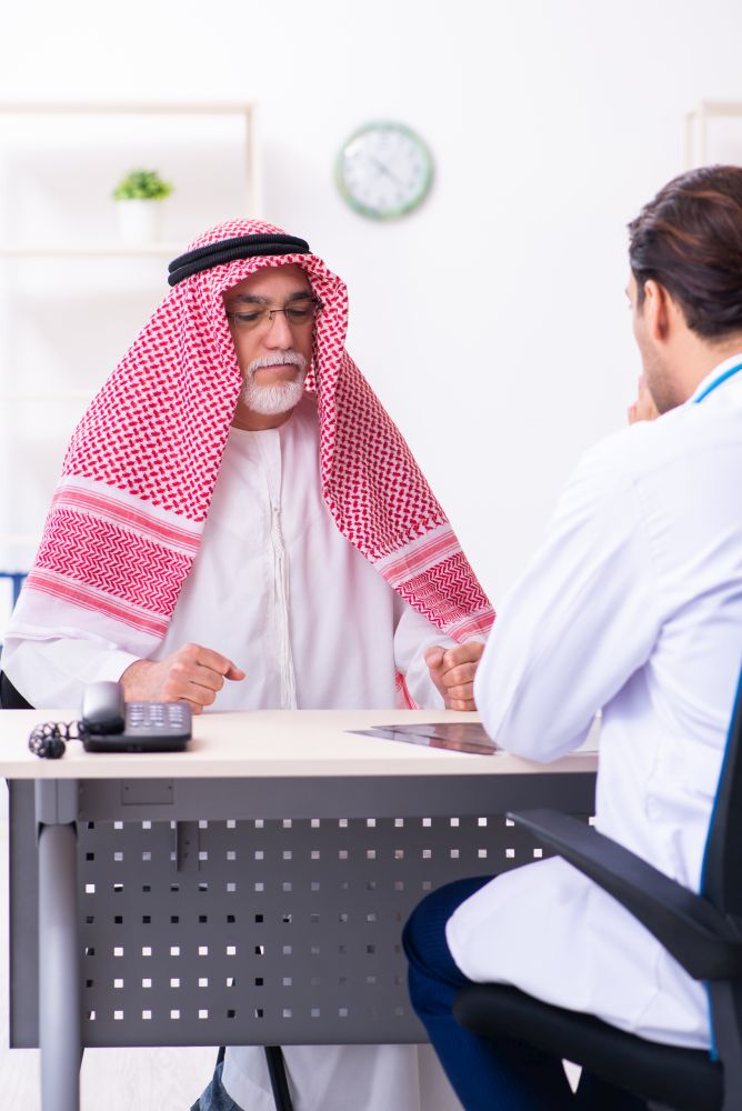 The old male arab visiting young male doctor. Old male arab visiting young male doctor