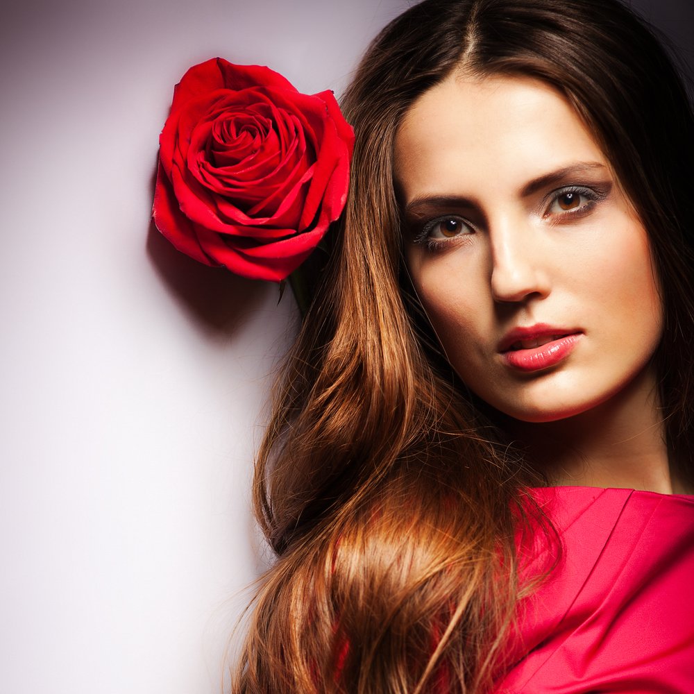 Beautiful dreaming girl with red roses in her hair