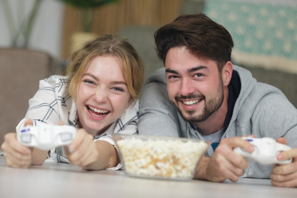 happy couple playing video-games and eating popcorn