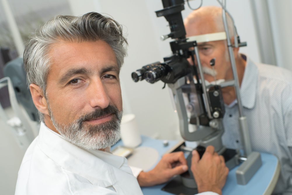 happy optometrist doing sight testing to senior patient