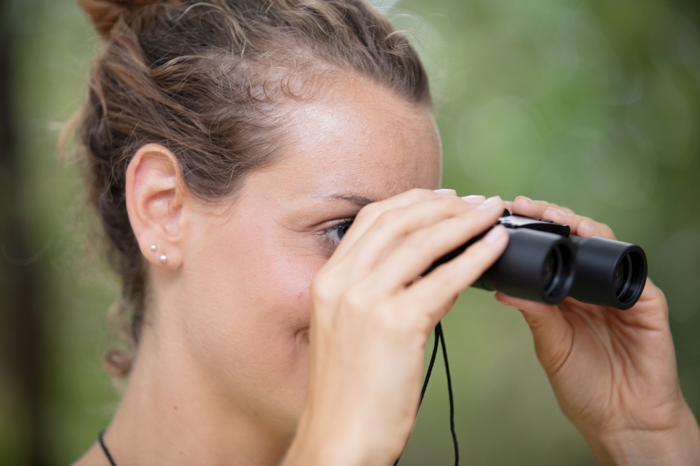 woman with binoculars in the forest