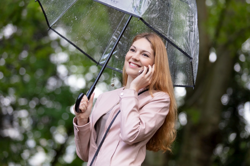 woman on the phone holding umbrella out in the rain