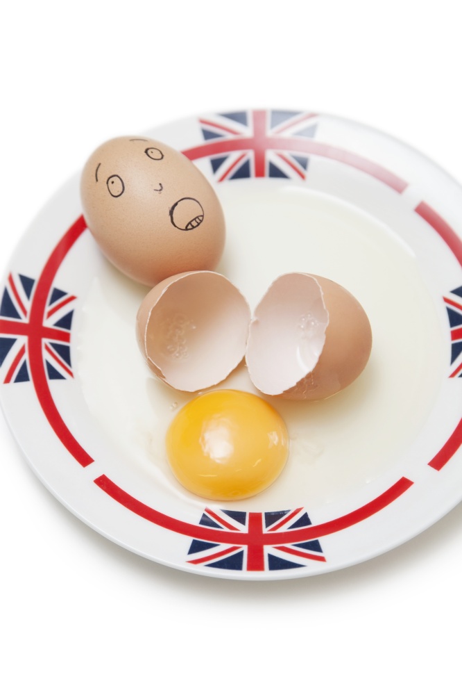 Anthropomorphic brown egg with egg shells and yoke in plate