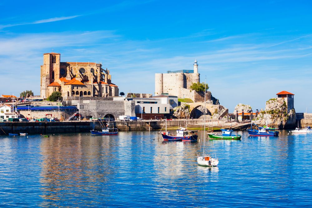 Boats at the port of Castro Urdiales, Santa Maria Church and Santa Ana Castle Lighthouse in Cantabria region in northern Spain.