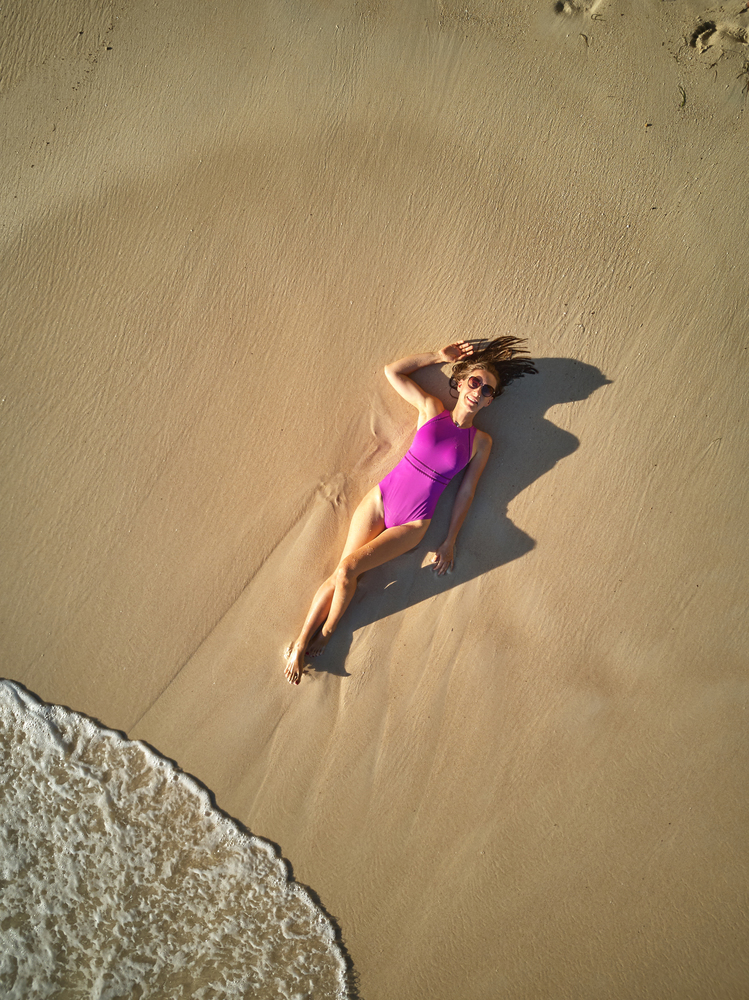 Woman lying down on beach aerial top view drone shot at Seychelles, Mahe