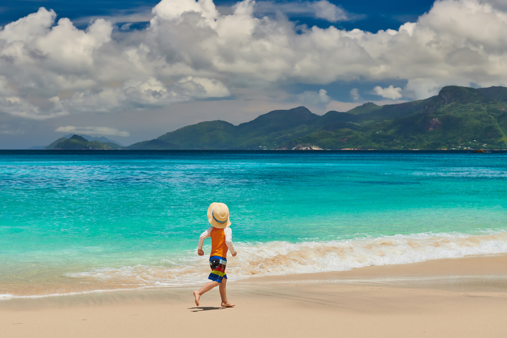 Three year old toddler boy running on beach. Summer family vacation at Seychelles, Mahe.