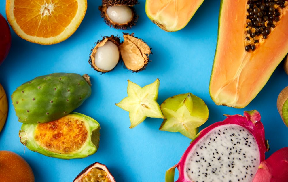 food, summer and healthy eating concept - different exotic fruits on blue background. different exotic fruits on blue background