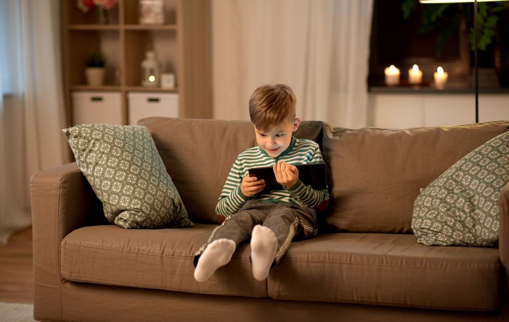 childhood, technology and people concept - happy smiling little boy with tablet pc computer at home in evening. happy little boy with tablet computer at home