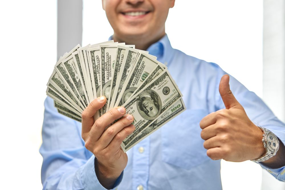 business, people and finances concept - close up of smiling businessman with american dollar money showing thumbs up. smiling businessman with money showing thumbs up