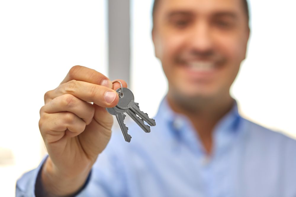 real estate, housing and people concept - close up of smiling man holding house keys. close up of smiling man holding house keys