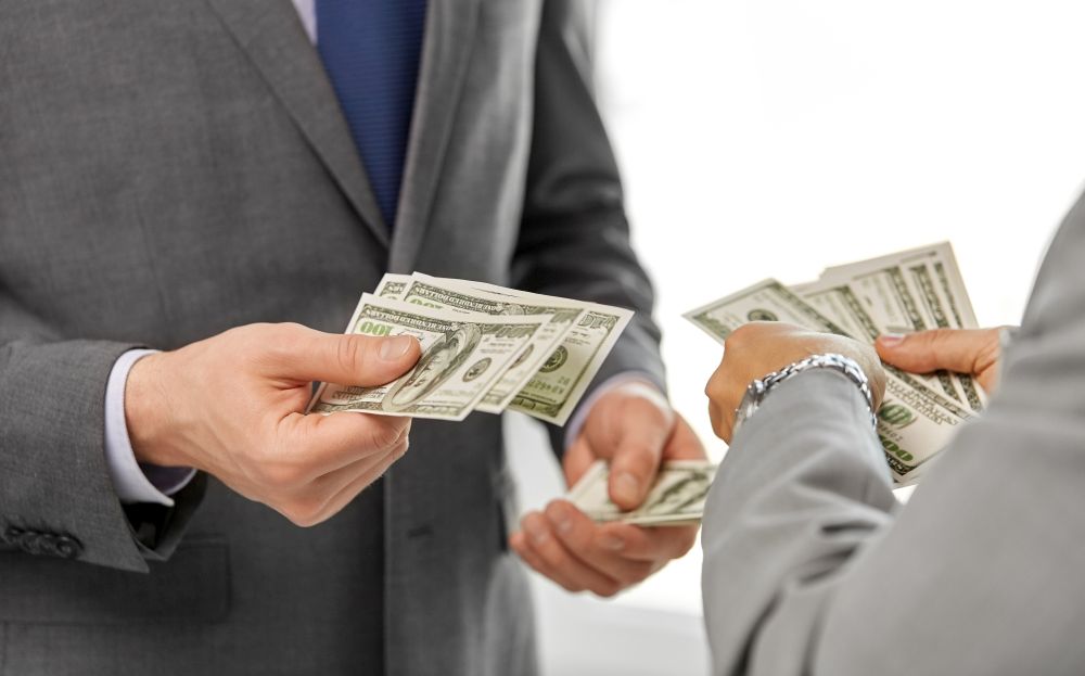 business, people and finances concept - close up of businessmen&rsquo;s hands holding american dollar money. close up of businessmen&rsquo;s hands holding money