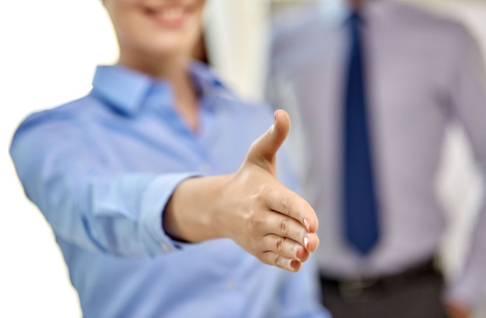 business people, cooperation, partnership and deal concept - close up of businesswoman making handshake gesture at office. businesswoman making handshake at office