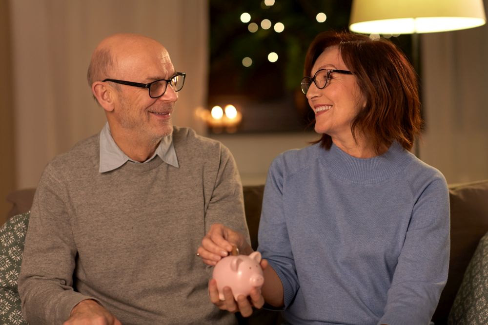 finance, savings and people concept - happy senior couple with piggy bank at home. happy senior couple with piggy bank at home